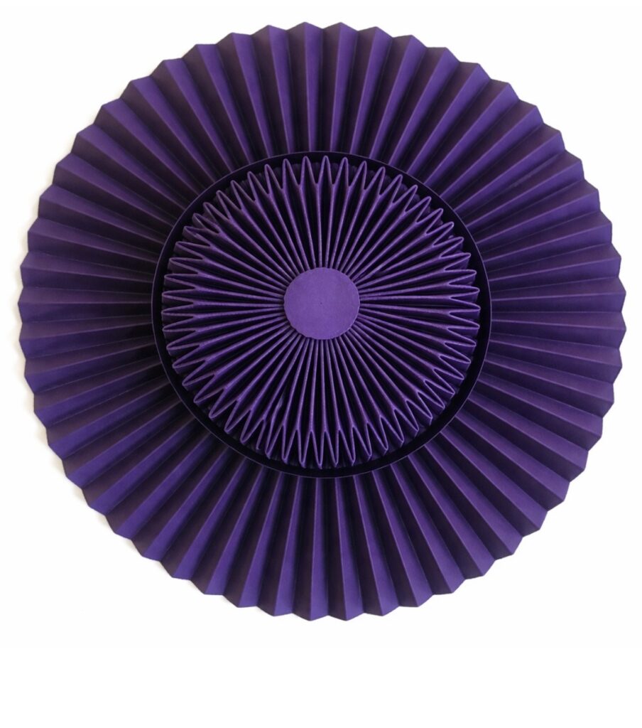Chapeau violet réalisé en papier plissé, mettant en valeur les volumes, la texture et la précision du plissage contemporain.