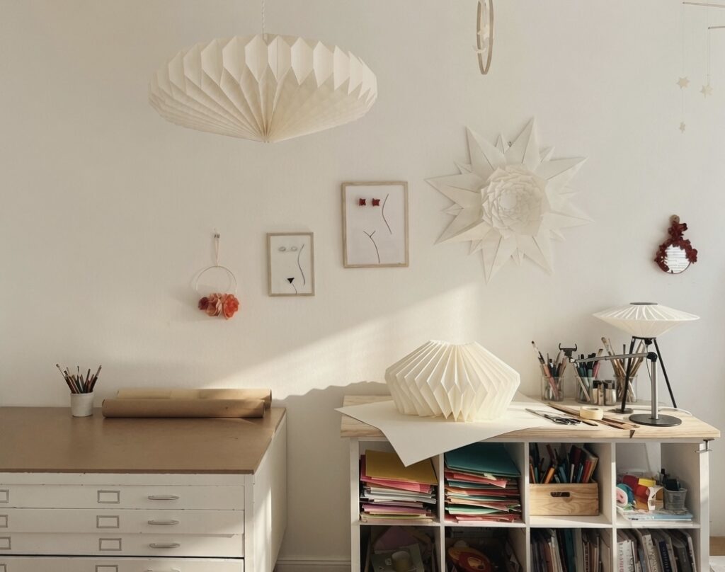 Vue de l'atelier DesignPapierAVD avec des suspensions en papier, des œuvres en origami accrochées au mur, un espace de création et un meuble de rangement dédié aux papiers.