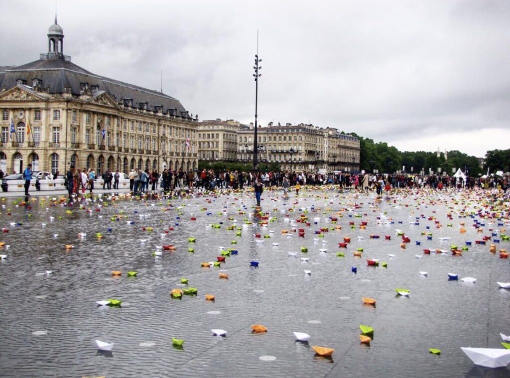 Vue du Miroir d'Eau de Bordeaux recouvert de 12 446 bateaux en origami lors de l'installation artistique Miroir Magique.